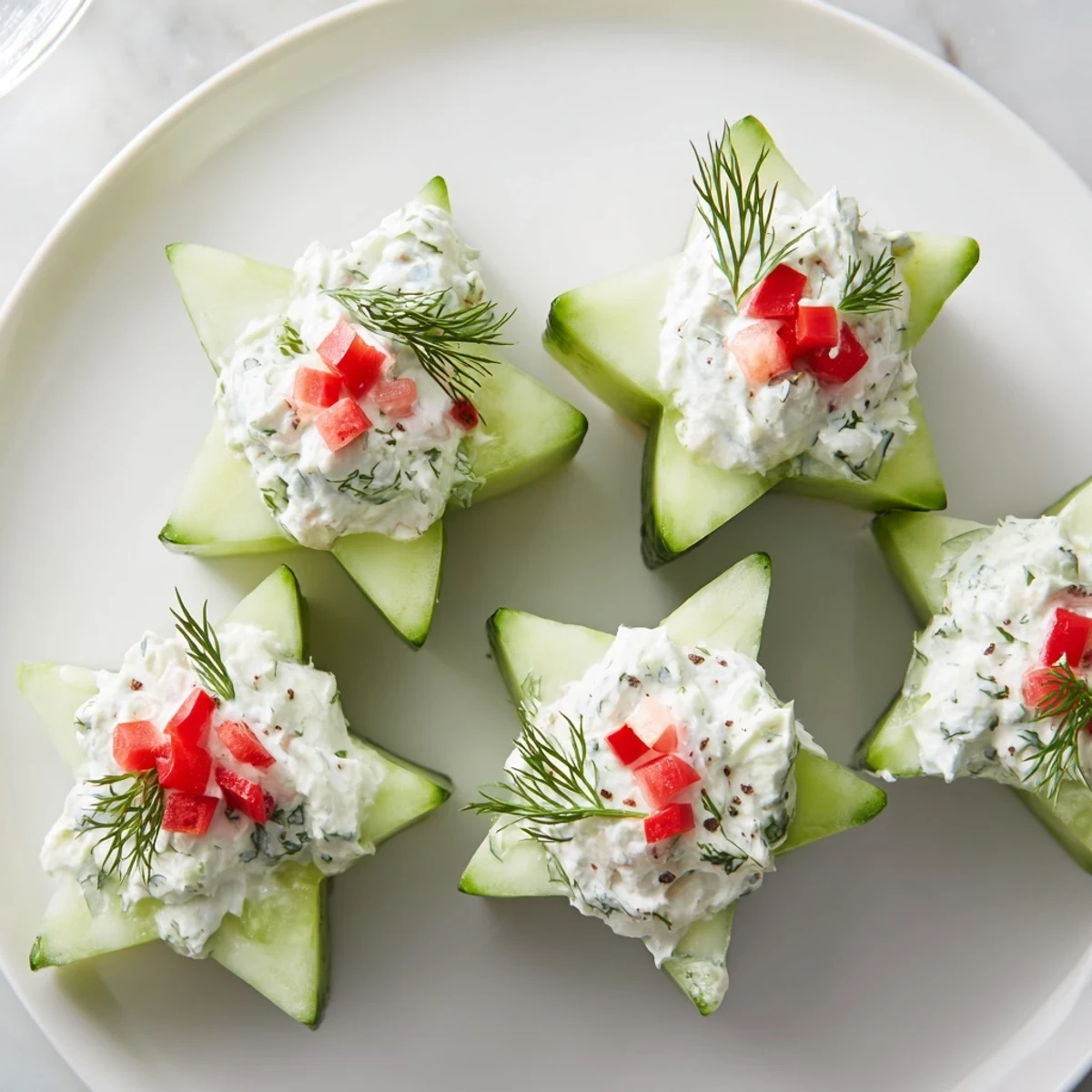 Close-up of freshly made Cucumber and Dill Christmas Stars, garnished with red pepper and dill sprigs.