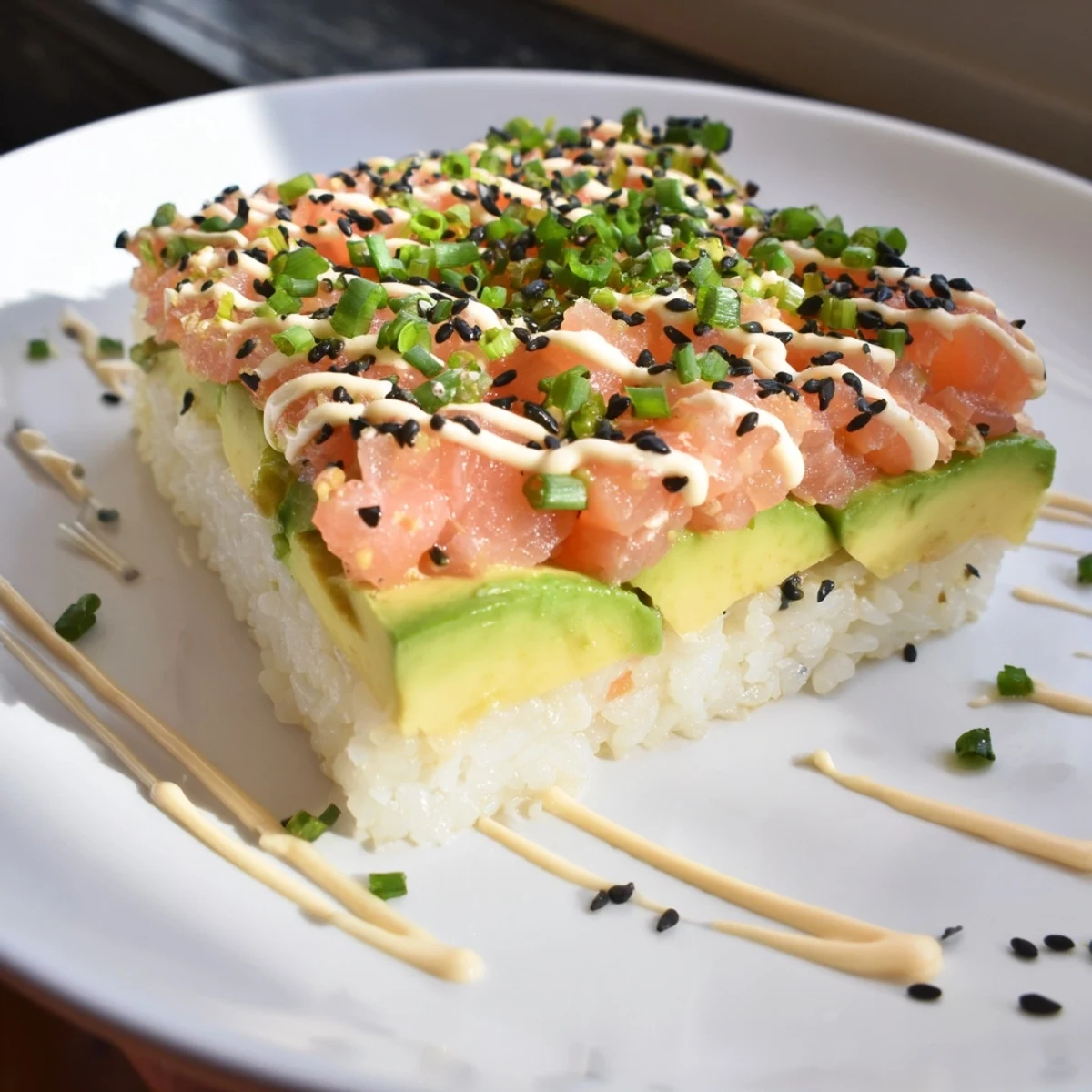 Golden crispy rice salmon stack topped with creamy avocado and spicy mayo, perfect appetizer.
