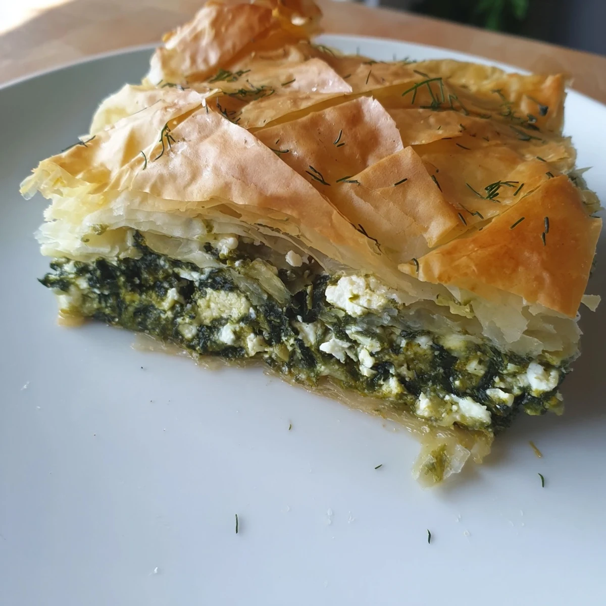 A close-up of a freshly baked Greek spanakopita, showing the crisp, golden crust and filling.