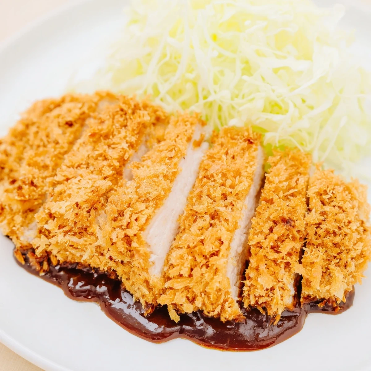 Crispy Japanese Chicken Katsu cutlet fried to perfection, accompanied by a savory tonkatsu dipping sauce and fluffy white rice.