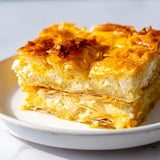 Freshly baked Serbian Gibanica, a savory cheese pie, showcases layers of phyllo, wonderfully crisp.