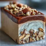 A hand holding a piece of chewy Hojicha Nougat, revealing the roasted green tea color.