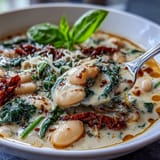 Hearty bowl of creamy white bean soup featuring tender vegetables, cannellini beans, and a swirl of heavy cream for richness.  