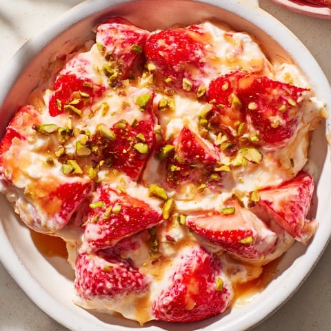 Yogurt Dipped Strawberry halves coated in creamy yogurt, sprinkled with nuts, ready for a delicious dessert.