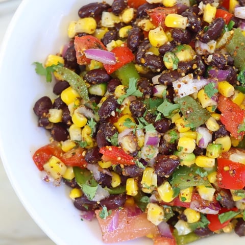 A colorful bowl of Cowboy Caviar Salad featuring black beans and fresh vegetables, ready to eat.