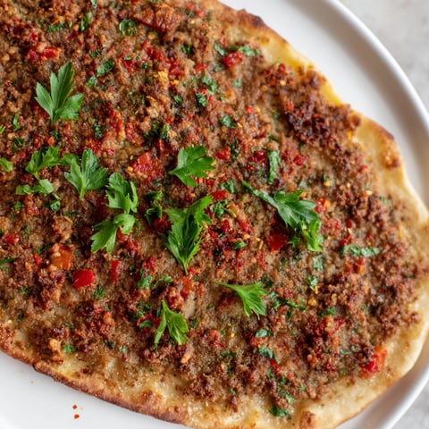 Golden-brown Turkish Lahmacun with a savory meat topping, perfect for a flavorful light meal.
