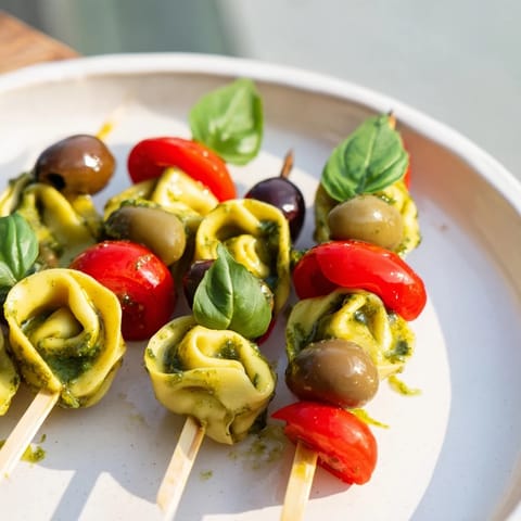 Vibrant Appetizer Skewers showcasing pesto-coated tortellini, juicy tomatoes, and briny olives, delicious.