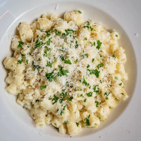 A steaming bowl of 15-Minute Garlic Parmesan Pasta, generously dotted with freshly grated cheese.