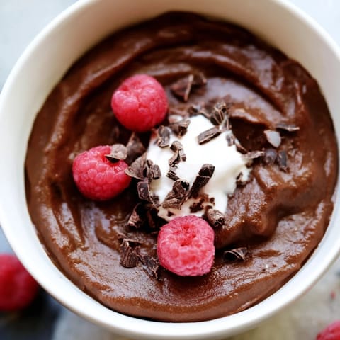 Creamy Avocado Chocolate Pudding, topped with fresh berries, ready for a delicious dessert.