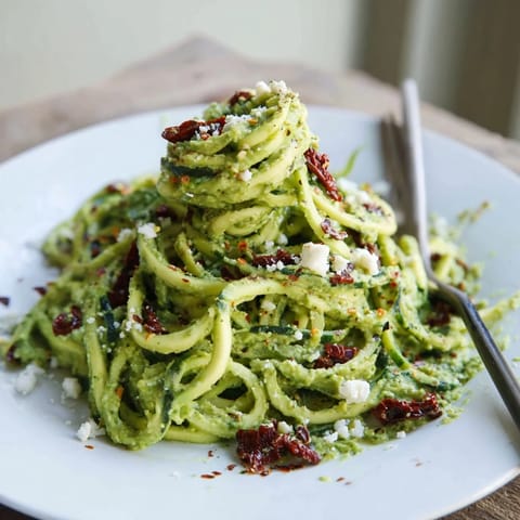 Creamy avocado pesto clings to tender zucchini noodles, topped with toasted pine nuts and a sprinkle of feta cheese, creating a rich and satisfying low-carb pasta alternative.