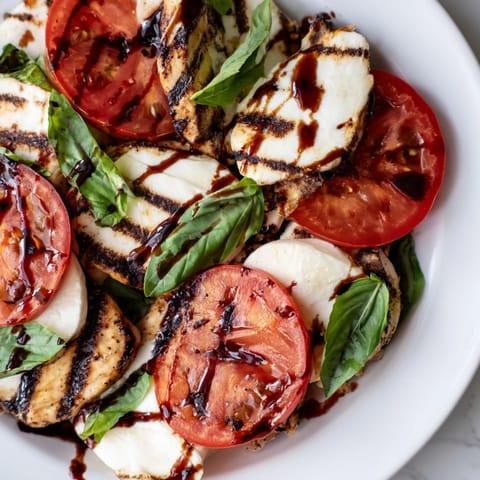 Juicy grilled chicken caprese salad with colorful tomatoes and creamy mozzarella, ready to serve for a light summer lunch.