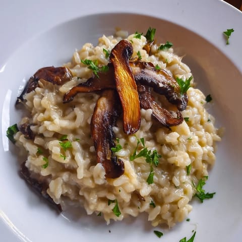 Steam rises from a warm bowl of Roasted Mushroom Risotto, showing its rich texture and golden, herb-infused mushrooms paired with fluffy arborio rice.  