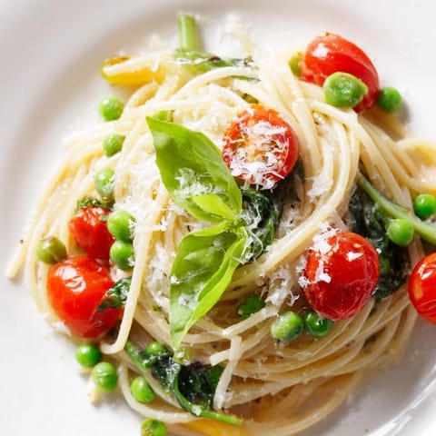 Hearty Spring Veggie One-Pot Spaghetti served in a white bowl, garnished with grated Parmesan and fresh basil leaves against a cozy kitchen backdrop.