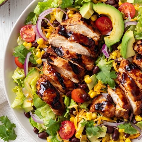 A fresh honey lime chicken taco salad features juicy grilled chicken, cherry tomatoes, and shredded cheese on a bed of greens.