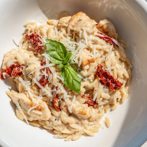 Creamy Tuscan Chicken Orzo with golden chicken, sun-dried tomatoes, and wilted spinach in a rich sauce.
