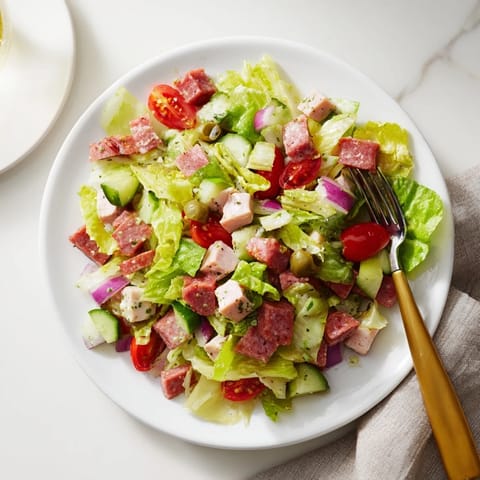 Chopped Italian Deli Chicken Salad in a white bowl, featuring cubes of chicken, salami, provolone, and colorful vegetables.