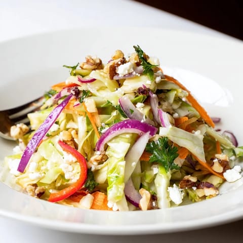 A vibrant Cooked and Loved Cabbage Salad features tender sautéed cabbage tossed with crisp carrots, red onion, and bell pepper in a tangy herb dressing.  
