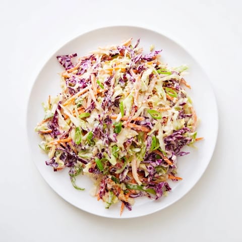 Crunchy shredded cabbage and carrots coated in creamy tangy dressing in a bowl, ready for serving with grilled meats.