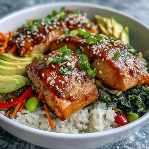 Golden-brown soy ginger salmon fillets glazed with sauce, served over fluffy jasmine rice with crisp vegetables in a white bowl.