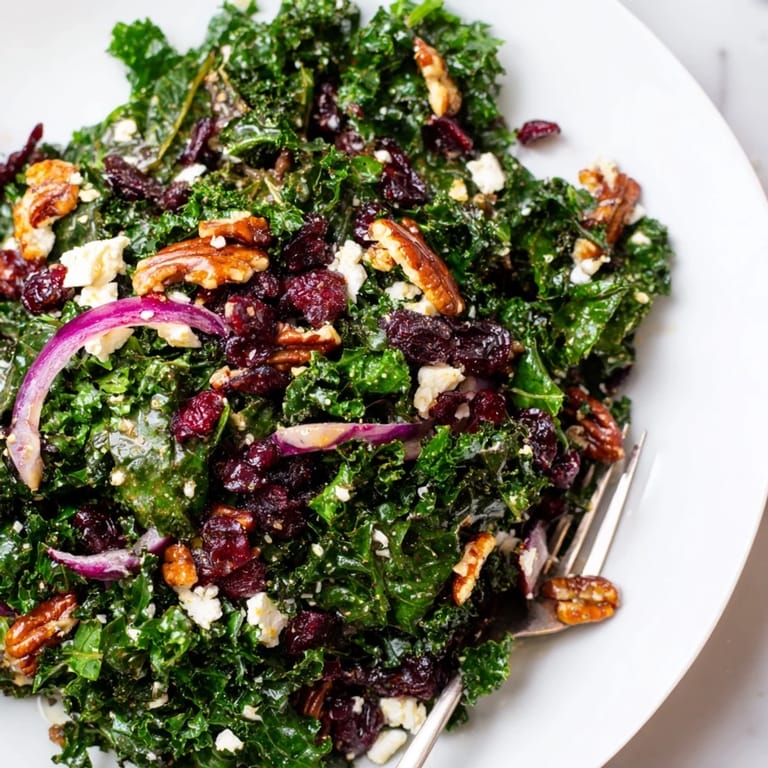 This vibrant warm kale salad with maple mustard dressing is topped with sliced red onion and crumbled feta on a serving platter.