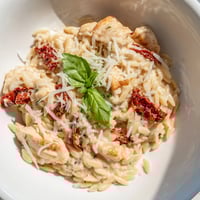 Creamy Tuscan Chicken Orzo with golden chicken, sun-dried tomatoes, and wilted spinach in a rich sauce.